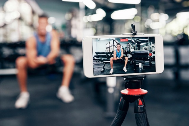 influencer fitness grabando rutina de ejercicios con móvil sobre trípode