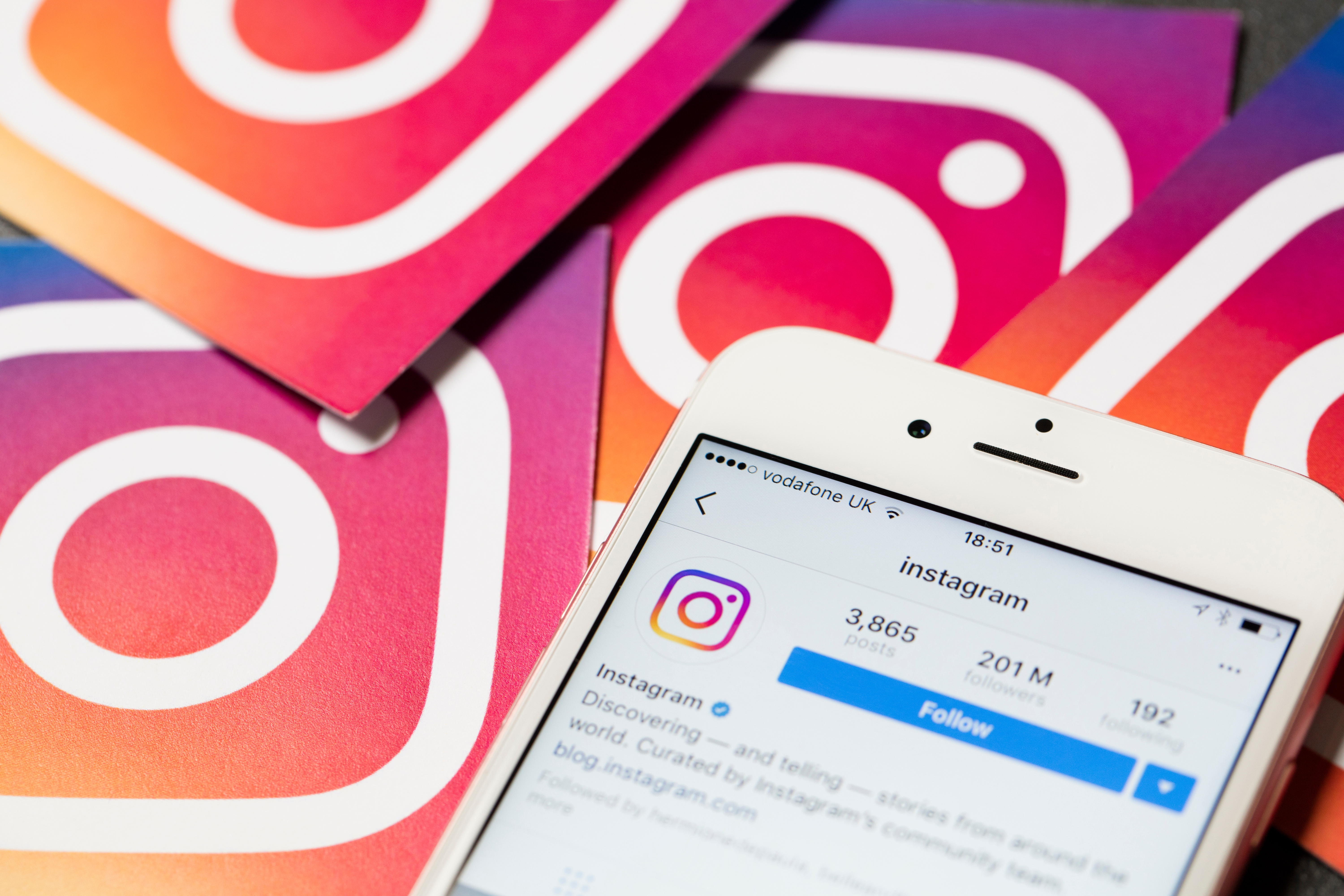 Smartphone mostrando el perfil de Instagram sobre varios logotipos de la plataforma, representando estrategias de Social Media Search Optimization para mejorar la visibilidad del contenido.