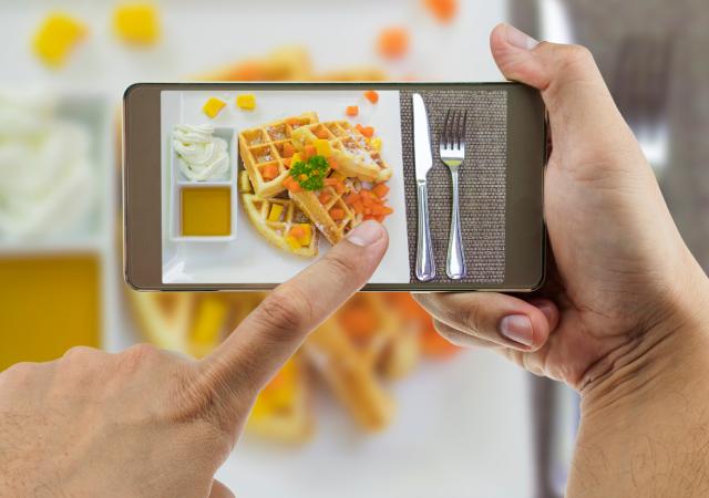 Persona fotografiando un plato de comida con un móvil para crear contenido de marketing alimentario